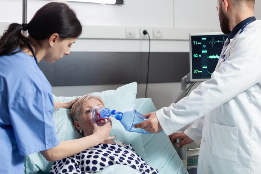 Medical team helping senior woman patient laying in hospital bed